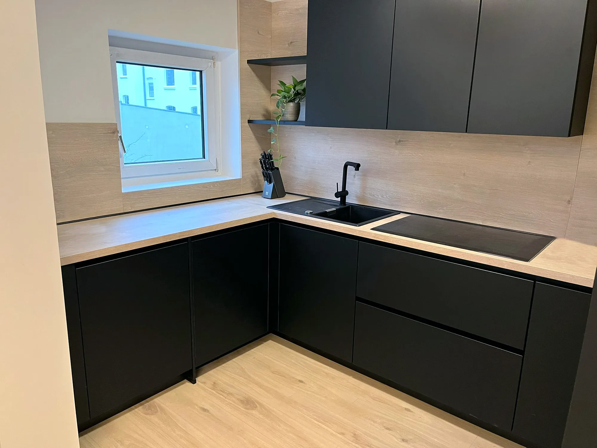 Moderne schwarze Küche mit Fenster über der Spüle und Holzarbeitsplatte – Referenz von SORI Studios